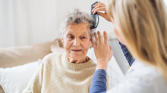 Care worker brushing older lady's hair.